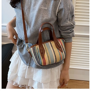 Detail view of colorful woven straw bag with contrast stripes and adjustable brown strap