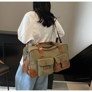 Detail of army green canvas travel bag with leather straps and front pockets worn by model