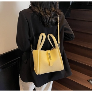 Detailed view of yellow litchi pattern leather bucket bag with metallic gold buckle