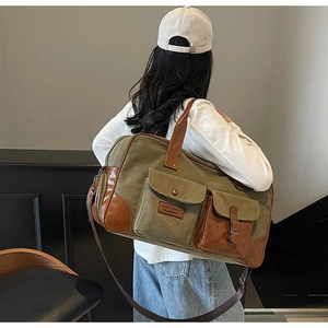 Detail of canvas travel bag featuring olive green fabric and brown leather accents