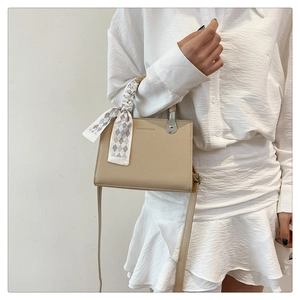 Detailed macro view of litchi texture faux leather and elegant checkered bow on the beige bag
