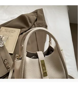 Détail du sac seau en cuir grainé blanc cassé avec fermoir doré dans un décor lifestyle