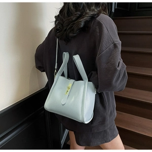 Detail of light blue lychee pattern leather handbag with gold metal clasp and shoulder strap