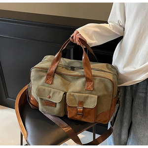 Detail of army green canvas travel bag with brown leather accents and dual front pockets