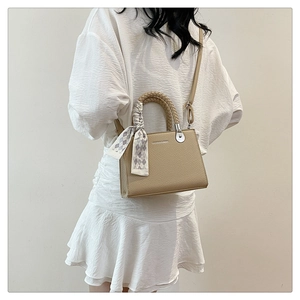 Detail of lychee textured tote bag with silk scarf handle on white dress model
