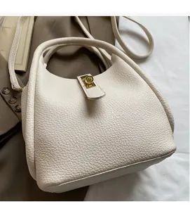 Détail du sac seau en cuir grainé blanc avec fermoir pivotant doré et poignée