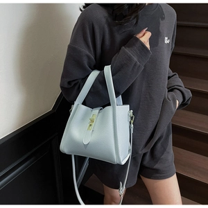 Detail of light blue lychee texture handbag featuring gold metal clasp and sturdy handle