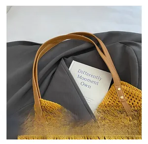 Detailed close-up of yellow knit tote bag featuring color accents and leather handles