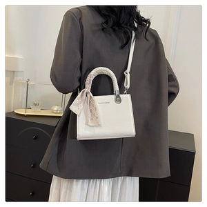 Detail of white litchi pattern handbag featuring woven handle and silk scarf accessory