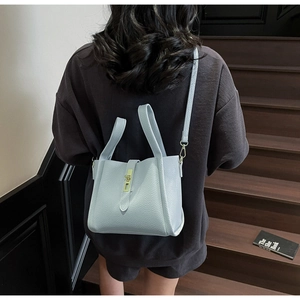 Detail of light blue lychee pattern handbag featuring a gold buckle on model shoulder