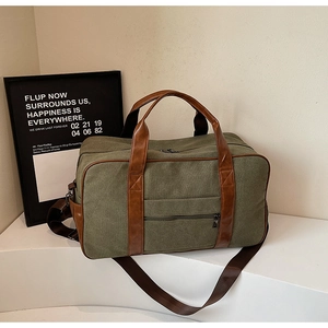 Detail view of olive canvas travel bag with brown leather handles and side zipper pocket