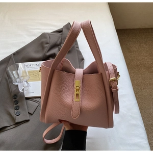 Detail of pink lychee leather handbag with gold twist lock and elegant top handle