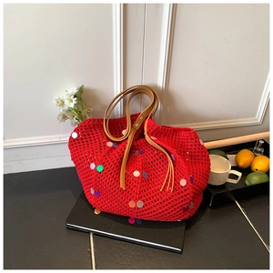 Close-up of red knit tote bag featuring colorful sequins and premium brown leather handles