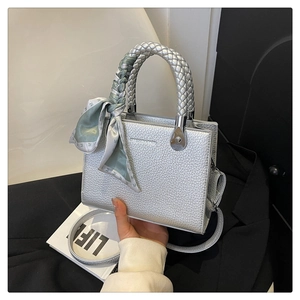 Detail of silver litchi grain square bag with woven handle and silk scarf accessory