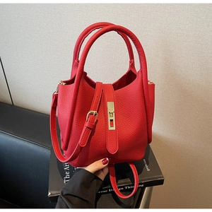 Gros plan sur le sac en cuir rouge à motif litchi avec fermoir doré et bandoulière longue