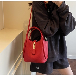 Détail du sac à main rouge en cuir grainé avec fermoir doré et bandoulière assortie