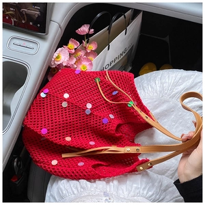 Macro shot of red knit tote bag with colorful sequins and brown leather straps