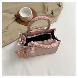 Close-up of pink litchi grain leather bag with woven handle and plaid silk scarf