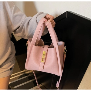 Detailed view of pink lychee leather bucket bag with golden buckle and crossbody strap