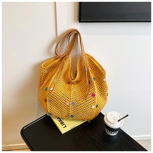 Detail of yellow knit crochet tote bag with colorful sequins and brown leather handles