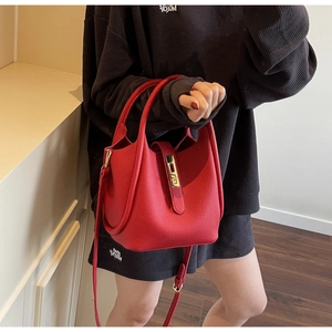 Détail du sac seau en cuir grainé rouge avec fermoir doré et fine bandoulière ajustable