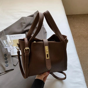 Deep brown litchi pattern leather handbag with gold buckle shown with a blazer and magazine