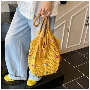 Detailed close-up of yellow knit tote bag featuring colorful sequins and brown leather handle