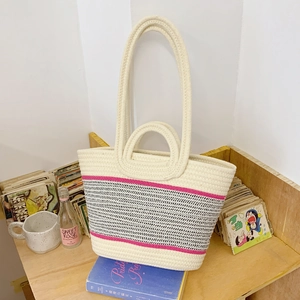 Large woven tote bag with pink and black stripes on a shelf with cozy room decor