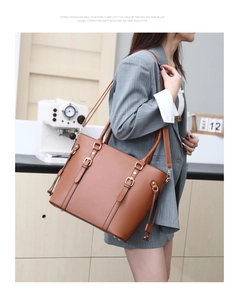 Brown faux leather tote bag with gold metal buckles shown on a model in a gray suit