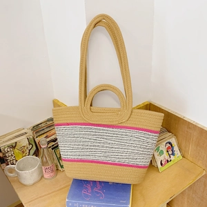 Large woven beach tote bag with pink stripes and dual handles on a minimalist wooden shelf