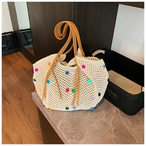 Close-up of hollow knit tote bag with colorful sequins and brown leather handles