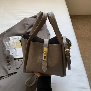 Detail view of lychee grain leather tote bag with gold swivel lock and adjustable strap