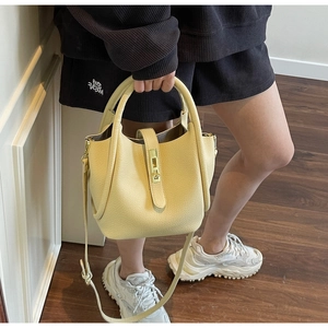 Détail d'un sac seau en cuir grainé jaune avec poignée supérieure et fermoir métallique