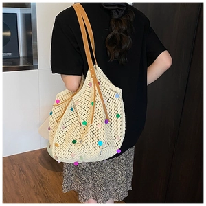Detail view of beige woven tote bag with colorful polka dots and brown leather straps