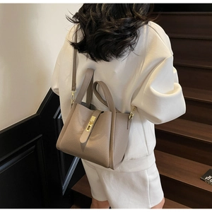 Detail of elephant grey lychee pattern leather bucket bag with metal buckle and strap