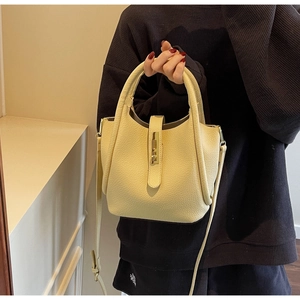 Détail du sac seau en cuir grainé beige crème avec fermoir rotatif doré et bandoulière fine