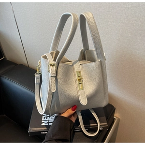 Detail of silver-grey lychee leather handbag with golden clasp and adjustable shoulder strap