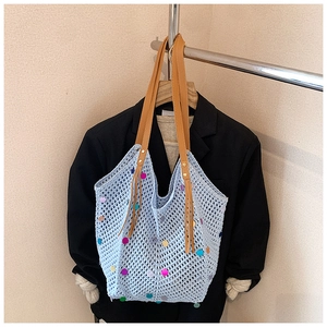 Close-up of light blue crochet bag with colorful sequins and brown leather handles
