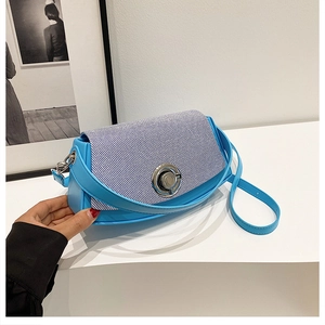 Detail of light blue crossbody bag featuring striped flap and silver twist-lock closure