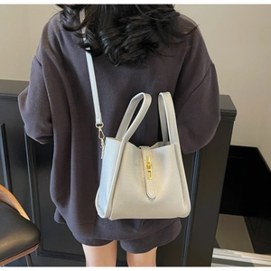 Detail view of the light grey pebbled leather bucket bag with golden buckle hardware