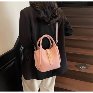 Détail du sac à main rose en cuir grainé avec boucle dorée porté par un mannequin