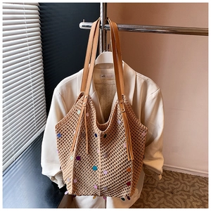 Detail of straw woven tote bag featuring colorful sequins and leather tassel decoration