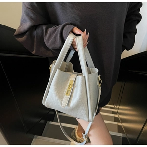 Detail of light gray lychee grain leather handbag with gold twist lock and handle