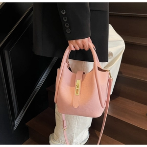 Détail du sac seau rose vif en cuir grainé avec fermoir doré et bandoulière élégante