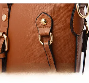 Macro detail of brown Saffiano leather texture and gold-tone metal hardware on tote bag