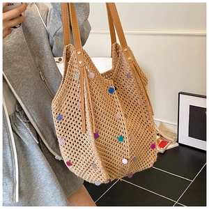 Detail of colorful sequins and brown leather handle on a beige woven shoulder bag