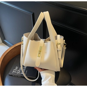 Detailed close-up of cream pebble leather texture and gold twist-lock on a handbag