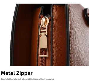 Detail of gold metal zipper and brown Saffiano faux leather texture on tote bag