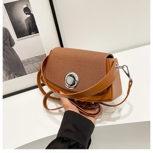 Close-up of woven brown leather crossbody bag with silver circular twist lock closure