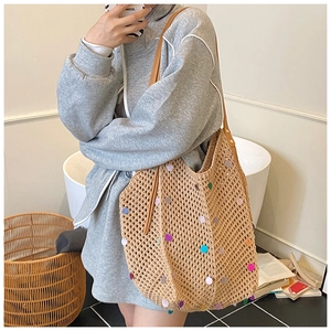 Close-up of beige crochet tote bag with colorful sequins and brown leather strap